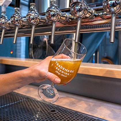 Photo of hand holding TMB pint glass being filled from beer tap