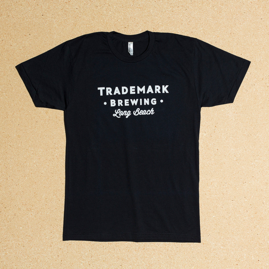 Photo of black t-shirt with large Trademark Brewing text logo on front side
